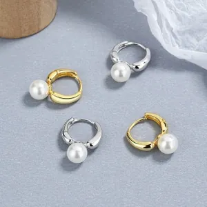 Detail view of gold and silver sterling silver pearl hoop earrings on a grey surface