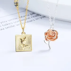 Dettaglio di ciondoli a rosa in argento 925 dorato e oro rosa su sfondo bianco