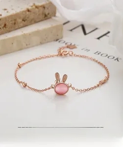 Detailed macro view of a rose gold rabbit bracelet with a pink cat eye stone