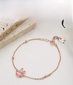 Close-up of S925 sterling silver heart tag and pink rabbit charm on rose gold bracelet