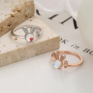 Close-up of rabbit silver rings with zircon ears and iridescent stone on stone background