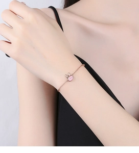 Close-up of rose gold silver bracelet with a pink cat eye stone rabbit charm on wrist