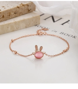 Detail of rose gold rabbit bracelet with pink opal stone and adjustable heart charm chain