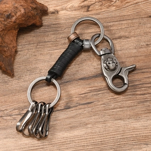 Vintage braided leather keychain with antique metal hardware on a rustic wooden desk