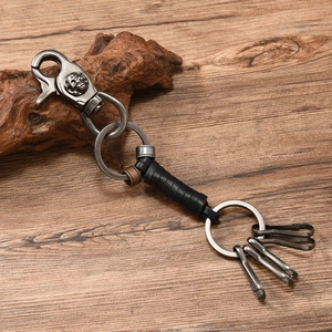 Retro punk braided leather keychain with skull carving on a rustic wood background