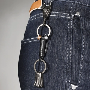 Vintage braided leather keychain with skull lobster clasp on denim pants