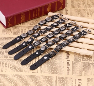 Lot de cinq bracelets punk en cuir noir avec rivets soleil, cœur et croix sur un support