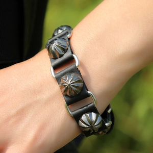 Détail d'un bracelet en cuir noir punk avec des clous en métal argenté et anneaux reliés