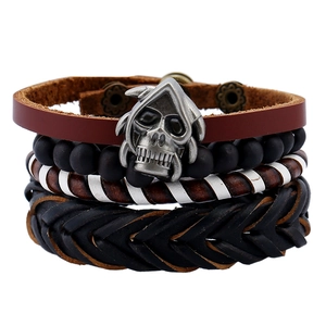 Dettaglio del set di bracciali in pelle multistrato con teschio e perline intrecciate