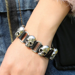 Macro detail of punk leather bracelet featuring four polished silver skull metal charms