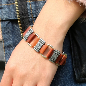 Gros plan d'un bracelet en cuir marron rétro avec des maillons en métal gravés