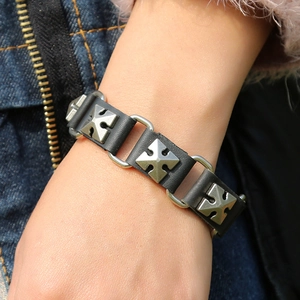 Detail of punk leather bracelet featuring silver cross studs and metal ring links
