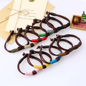 Handmade woven leather bracelets with colorful thread accents in a vintage gift display