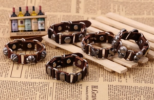 Macro detail of vintage punk leather bracelets featuring skull and cross metal charms