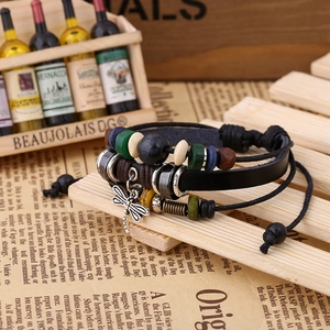 Detailed shot of a multilayered leather beaded bracelet with a metal dragonfly pendant