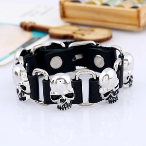 Détail d'un bracelet en cuir noir punk avec des têtes de mort en métal et fermoir à pression