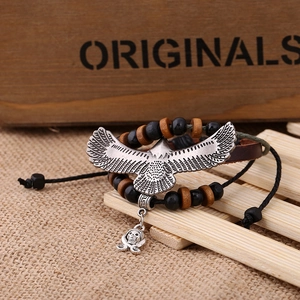 Detailed shot of multi-layer leather bracelet with eagle pendant and wooden beads on wood