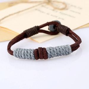 Macro detail of hand-braided dark brown leather bracelet with gray thread wrap