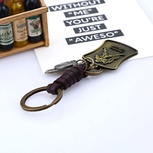 Détail du porte-clés Verseau vintage en cuir avec écusson en bronze et lanière tressée