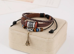 Detailed macro view of multilayer leather bracelet with bronze Eiffel Tower charm and beads
