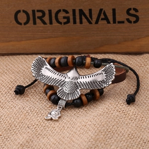 Macro detail of multi-layer leather bracelet with silver eagle and skull charms on burlap