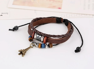 Macro detail of multi-layer leather bracelet with bronze Eiffel Tower charm and beads