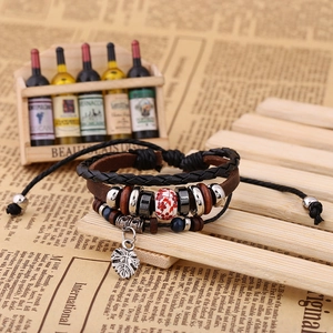 Detail of multi-layer leather bracelet with ceramic beads and leaf charm on wood stand