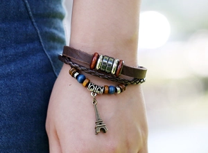 Close-up of multilayer leather bracelet with wooden beads and bronze Eiffel Tower pendant