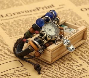 Vintage leather bracelet watch with brown braided strap and charms on retro newspaper