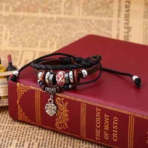 Retro multi-layer leather bracelet with ceramic beads and leaf pendant on vintage book