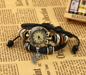Detailed view of a vintage multi-layer leather watch with bronze wing pendant and beads