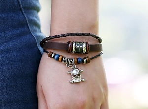 Close-up of a multi-layer brown leather bracelet with skull charm and wooden beads