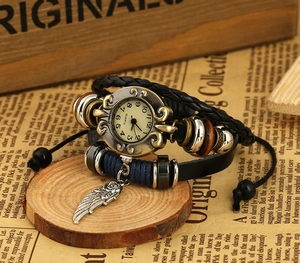 Detail of vintage leather wrap watch with braided straps, beads and silver wing pendant