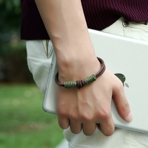 Retro braided leather bracelet in dark brown and green on a wrist holding a tablet