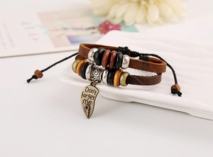 Détail d'un bracelet vintage en cuir tressé double avec breloque cœur gravée et perles en bois