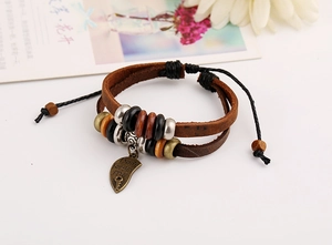 Détail d'un bracelet en cuir multicouche avec perles en bois et pendentif gravé