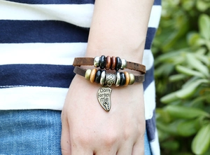 Détail d'un bracelet en cuir à perles avec breloque cœur en bronze gravé Don't forget me