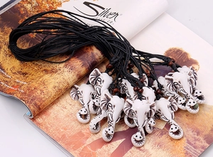 Detail of vintage ivory-style elephant pendants with wooden beads on black wax cords