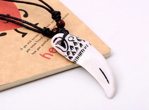 Collier tribal avec pendentif en forme de croc de loup blanc et gravures de totem noir