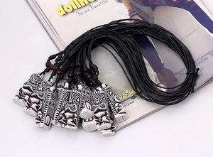 Detailed view of Tiki style resin pendants with adjustable black wax cord and wooden beads