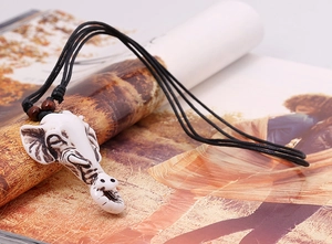 Detail of vintage elephant head pendant on black woven cord with wooden beads