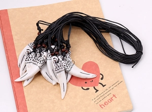 Vue macro de pendentifs dent de style tribal avec gravures et perles rouges