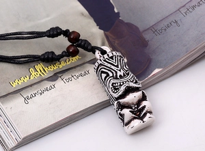 Macro shot of tribal Tiki pendant with black braided rope and brown wooden beads