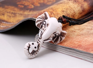 Detailed close-up of elephant head pendant with ivory finish and woven cord necklace