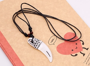 Gros plan du pendentif dent tribale avec gravure loup, cordon et perles en bois