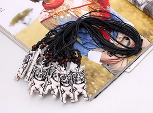 Détail de pendentifs tribaux en imitation d'os blanc avec gravures de totems noirs