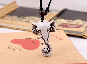 Close-up of ethnic elephant head pendant with black woven cord and wooden beads
