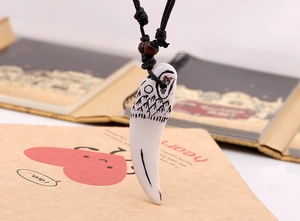 Détail du collier ethnique avec pendentif dent blanc et texture montagne gravée