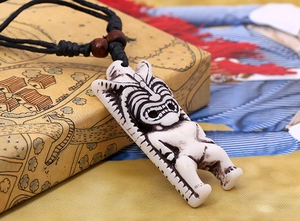 Vue macro d'un collier pendentif sculpté de style Tiki sur un coffret cadeau vintage