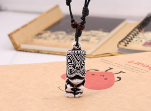 Macro detail of tribal tiki pendant with resin carving and black woven cord